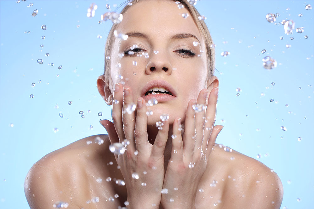 A person washing her face with waterDescription automatically generated